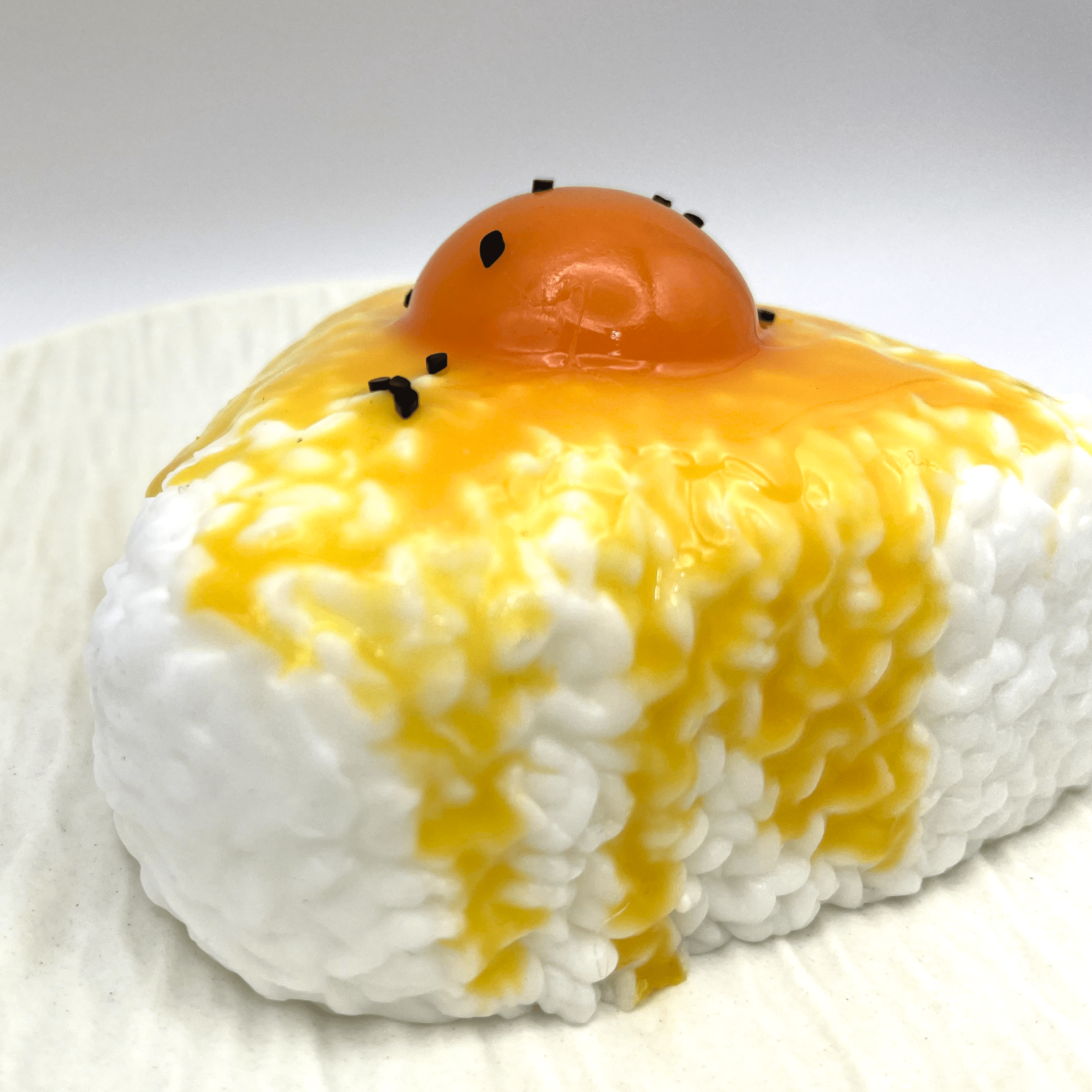 Close-up shot of the Egg Yolk Rice Ball Taba Squishy, focusing on the detailed texture and vivid colors