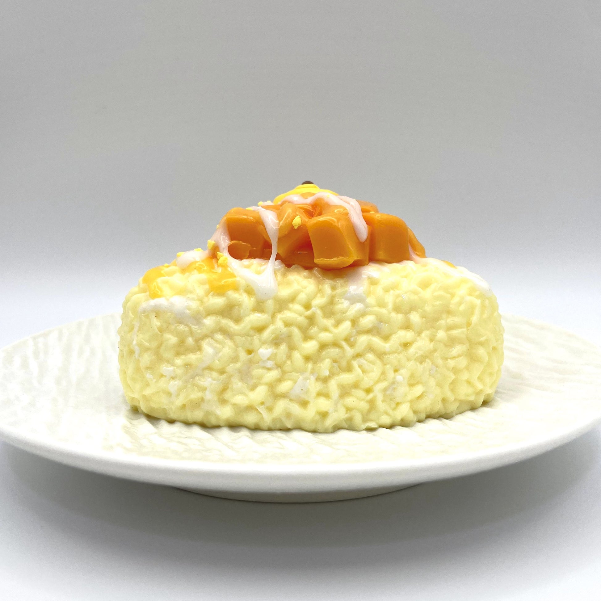 Front view of the Mango Rice Ball Taba Squishy, shaped like a soft and vibrant yellow rice ball."