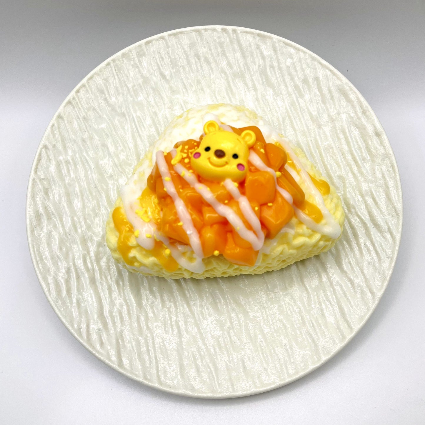 Top-down view of the Mango Rice Ball Taba Squishy, showcasing its delicate rice ball shape and mango-inspired color