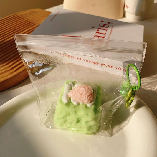 Matcha Berry Cube Taba Squishy in a clear packaging, showcasing its pastel green color and charming strawberry topping