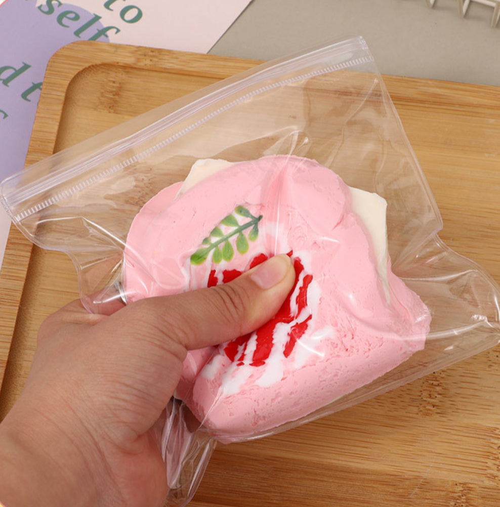 Hand squeezing Not a Strawberry Toast Taba Squishy, highlighting its soft, portable design