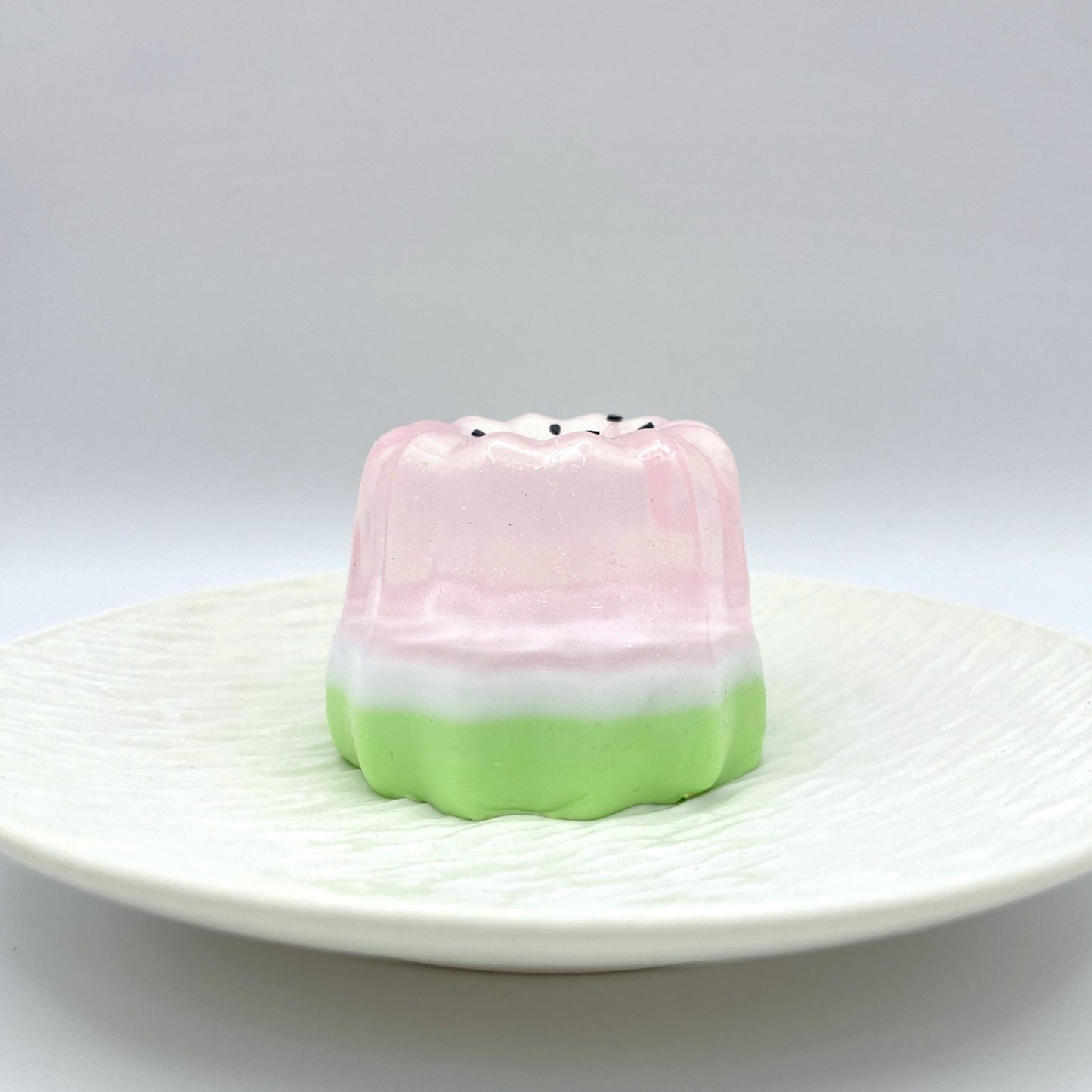 Sparkling Melon Canelé Taba Squishy in a delicate blend of translucent pink and green, featuring a subtle shimmer for a charming and calming effect