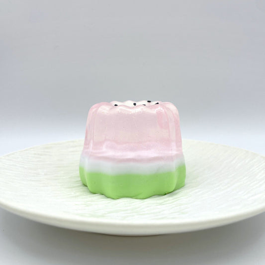 Sparkling Melon Canelé Taba Squishy in a delicate blend of translucent pink and green, featuring a subtle shimmer for a charming and calming effect